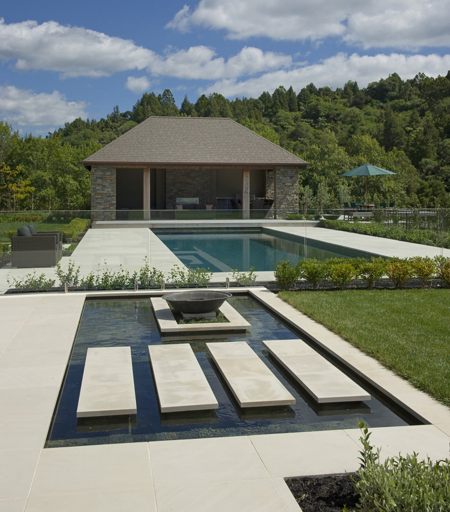 Pool and pool house with large pale stepping pads over a water feature