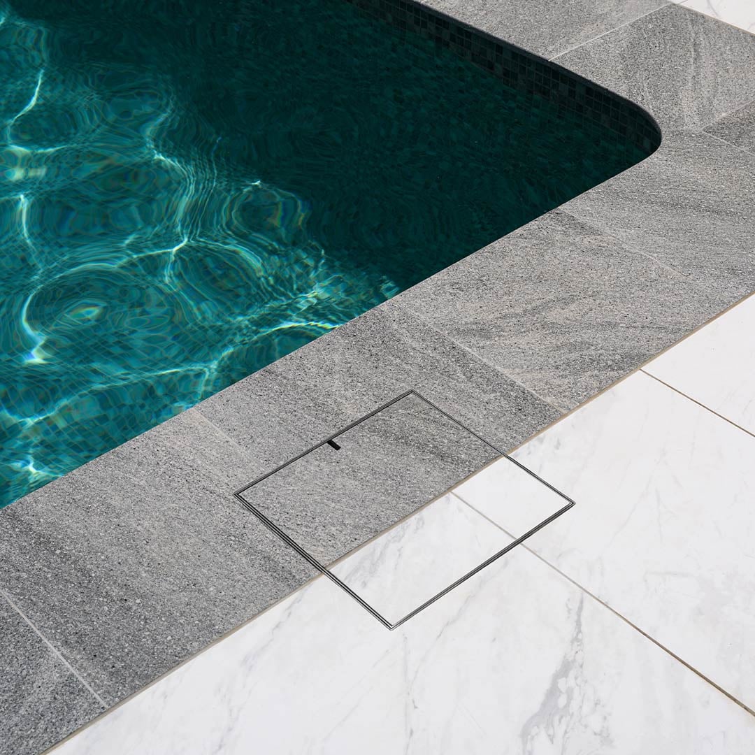 HIDE skimmer lid with paving inlay beside a pool