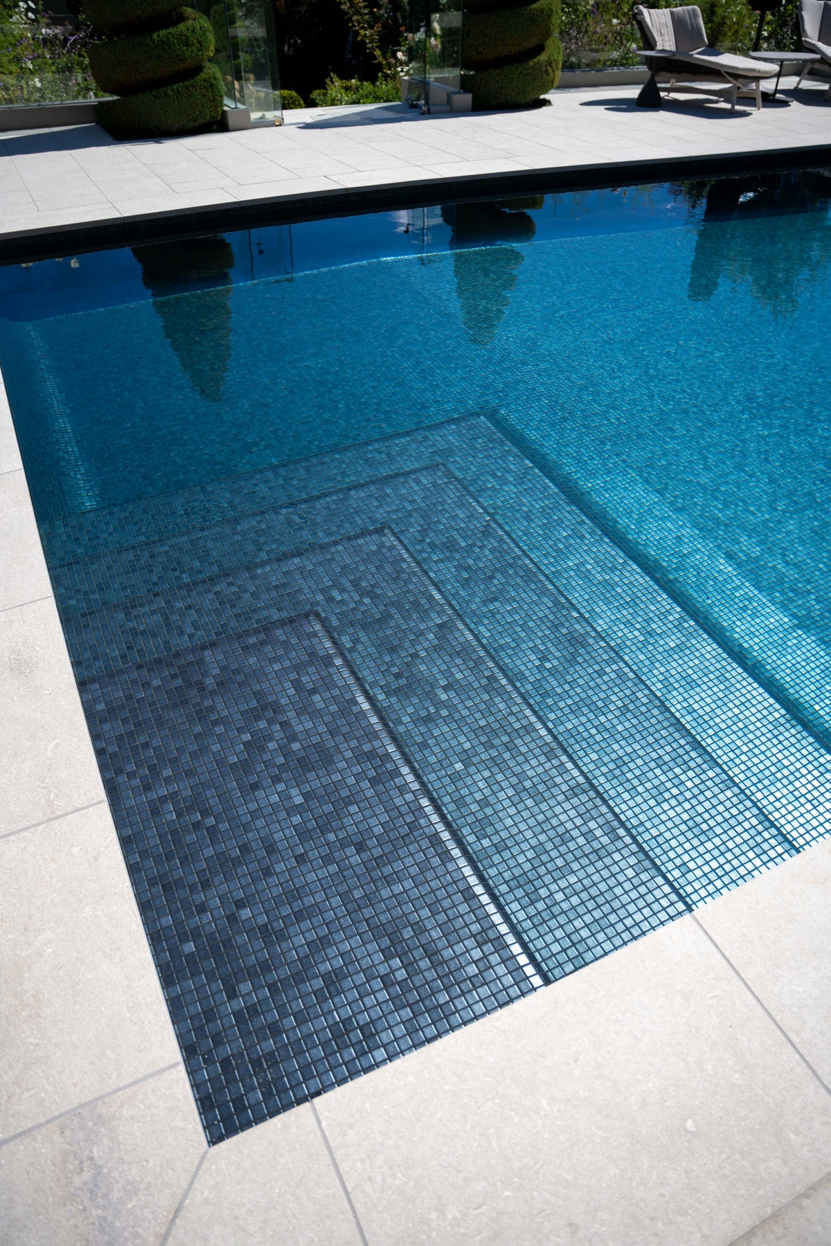 Pool with a dark mosaic interior and pale coping