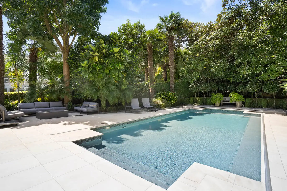 Sandstone pool surround with mosaic waterline in a tropical garden