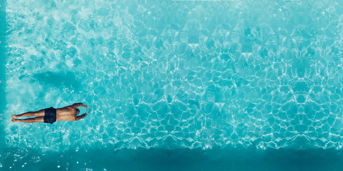 Swimmer floating in a pool finished in Ultra Quartz plaster